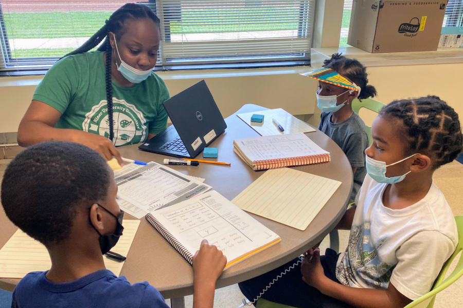 Keirra Crosland, 1st grade teacher at Niner University Elementary School sits with her students practicing long vowel sounds in a Sound Partners lesson at Niner University Elementary School SRC. She is serving as a Project ENRICH academic year mentor for teacher candidates. 

